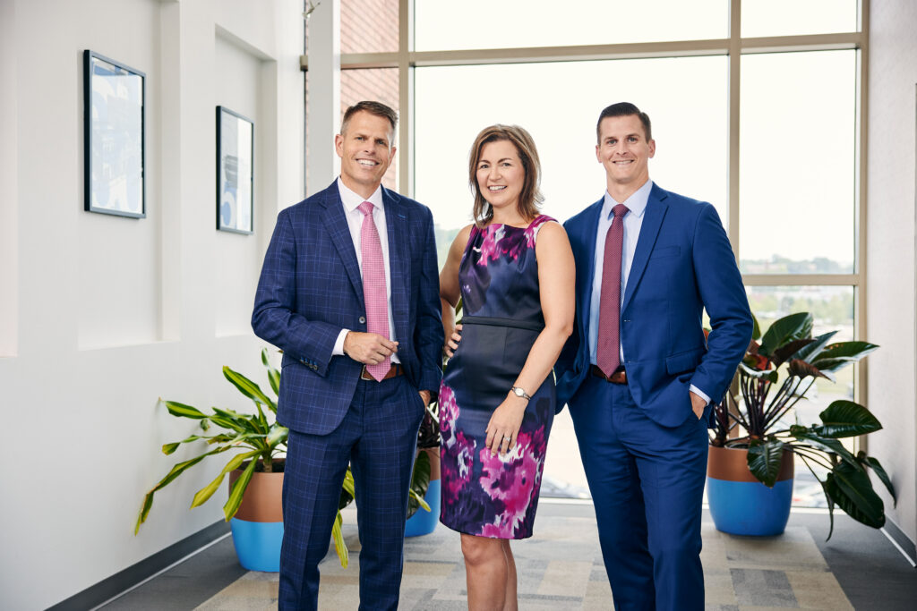 Red Tree Investment Group managers standing together in front of a glass wall, smiling for a picture